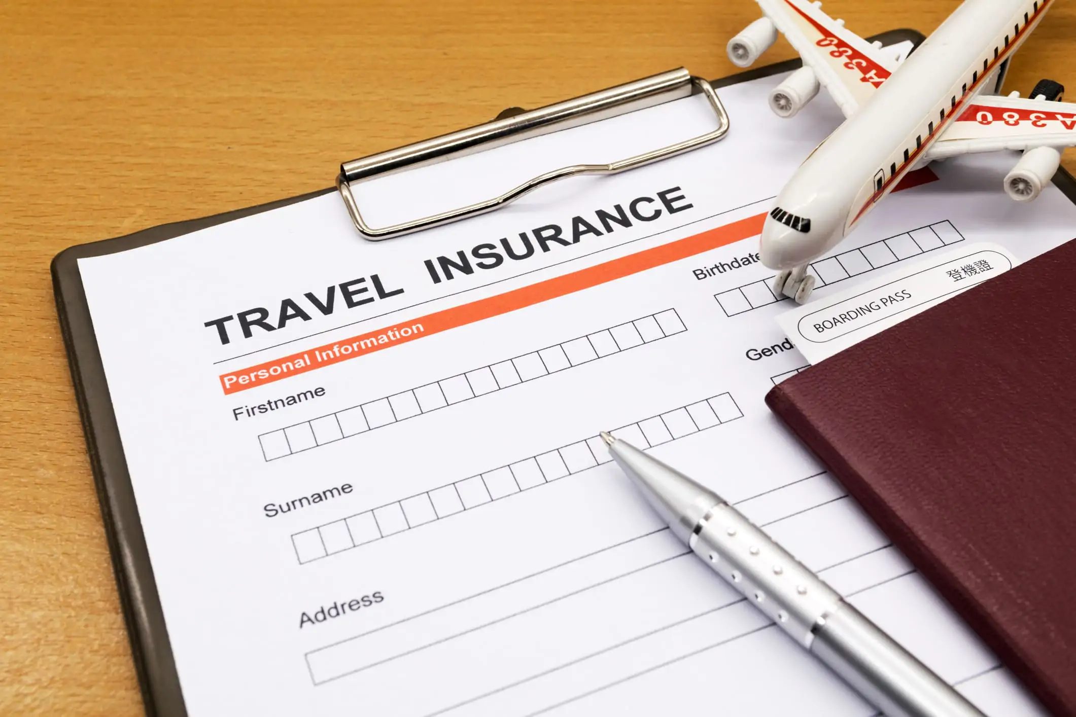 an image of a plane, a pen, a journal on top of travel insurance documents